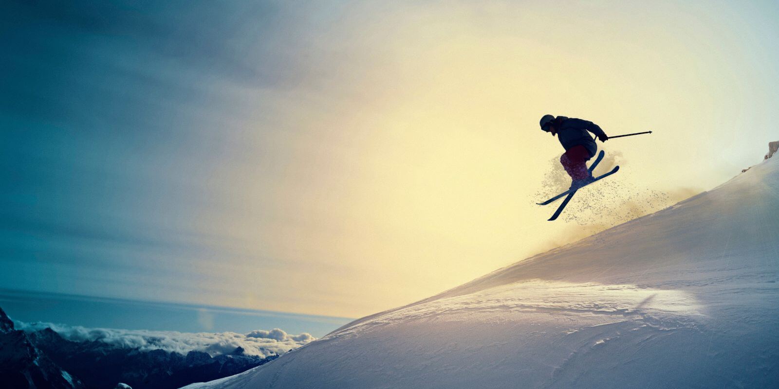 A person skiing down a hill with a burst of sun behind them