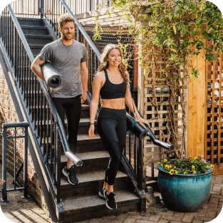 Two people descending stairs holding yoga gear, wearing Bracelayer compression pants, compression tights, knee support sleeve, knee compression sleeve, knee brace, brace knee, Vancouver knee brace, knees support